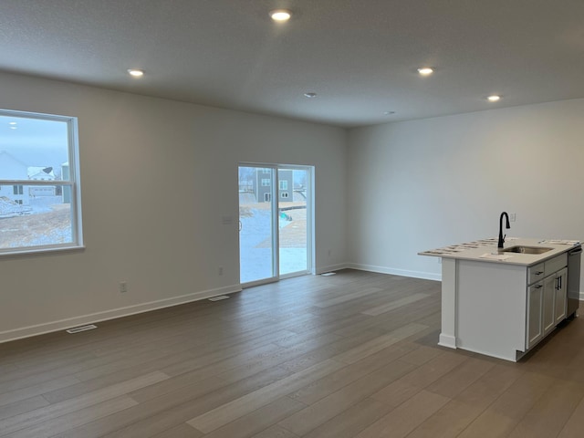 kitchen with white cabinetry, sink, a center island with sink, and light wood-type flooring