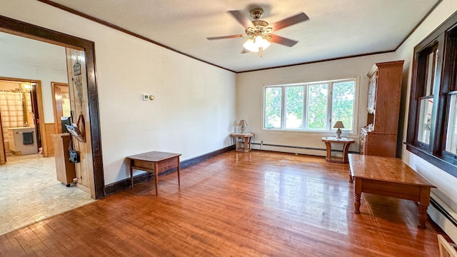 spare room with ceiling fan, a baseboard heating unit, ornamental molding, and light wood-type flooring