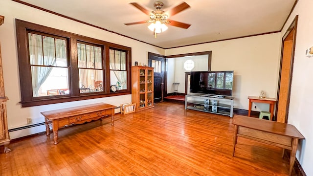 living room with ceiling fan, baseboard heating, wood-type flooring, and a healthy amount of sunlight