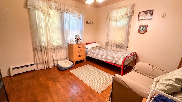 bedroom with baseboard heating and wood-type flooring