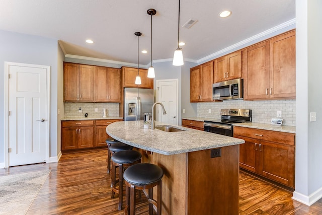 kitchen with sink, appliances with stainless steel finishes, backsplash, an island with sink, and decorative light fixtures