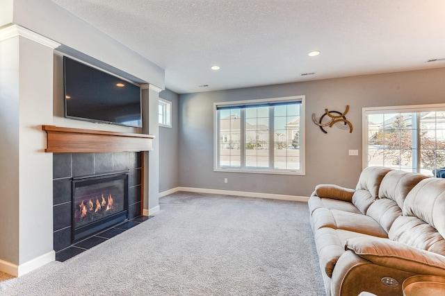 carpeted living room with a wealth of natural light, a textured ceiling, and a fireplace