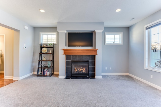 unfurnished living room with a tiled fireplace and carpet