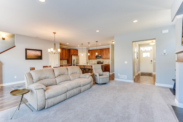 carpeted living room featuring an inviting chandelier