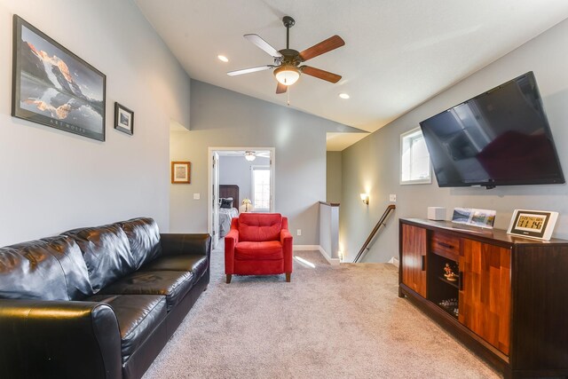 living room with ceiling fan, light colored carpet, and vaulted ceiling