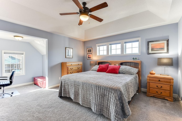 bedroom featuring ceiling fan, a raised ceiling, carpet floors, and multiple windows