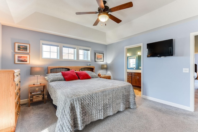 carpeted bedroom with connected bathroom, a tray ceiling, and ceiling fan