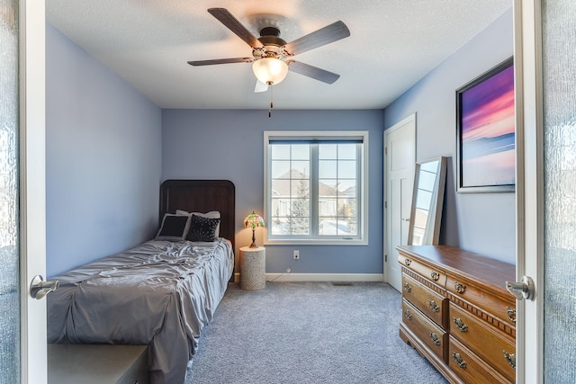 bedroom featuring ceiling fan, light carpet, and a textured ceiling