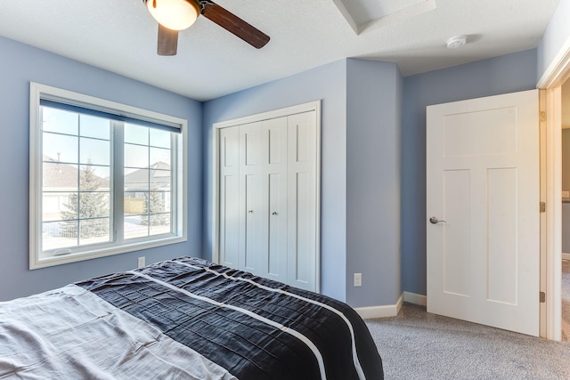 bedroom with carpet flooring, a textured ceiling, ceiling fan, and a closet