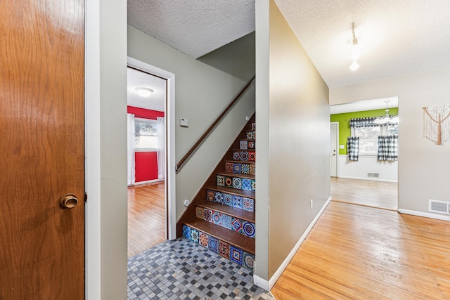 stairway with hardwood / wood-style floors and a textured ceiling