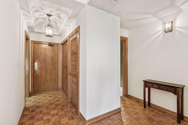 hallway featuring a textured ceiling and dark parquet flooring