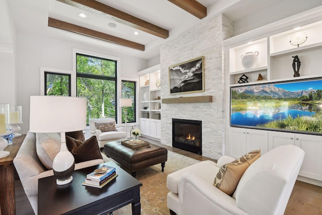 living room with wood-type flooring, built in features, beamed ceiling, and a fireplace