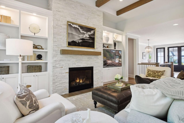 living room featuring beamed ceiling, a fireplace, built in shelves, an inviting chandelier, and dark hardwood / wood-style flooring