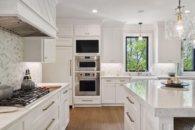 kitchen with premium range hood, white cabinetry, hanging light fixtures, and appliances with stainless steel finishes