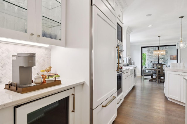 kitchen with crown molding, white cabinets, decorative light fixtures, light stone counters, and beverage cooler