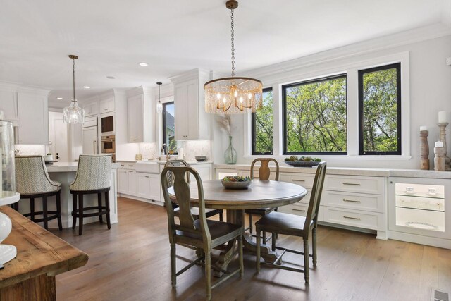 dining room with an inviting chandelier, dark hardwood / wood-style floors, ornamental molding, and a healthy amount of sunlight