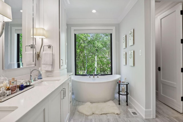 bathroom featuring ornamental molding, vanity, and a bathing tub