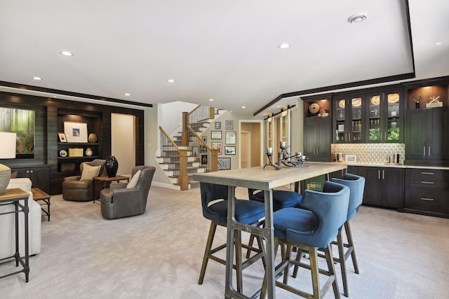 carpeted dining room featuring ornamental molding, a barn door, and indoor bar