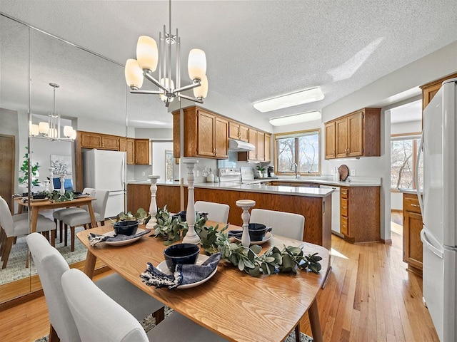 dining space featuring an inviting chandelier, light wood-style floors, and a textured ceiling