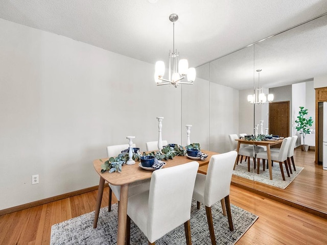 dining area featuring light wood-style flooring, baseboards, and a chandelier