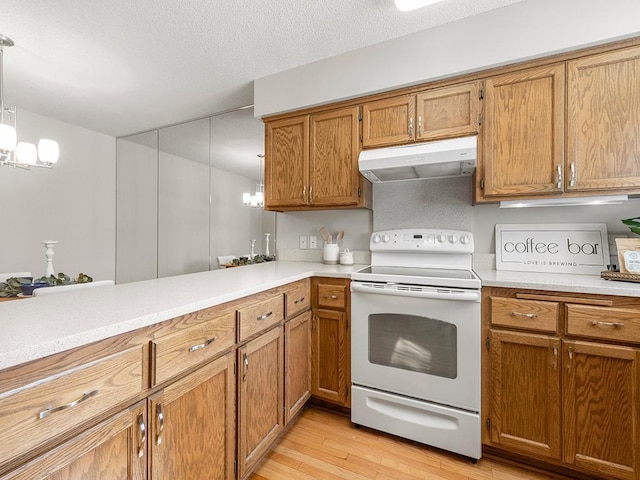 kitchen featuring under cabinet range hood, white electric stove, light countertops, and brown cabinetry