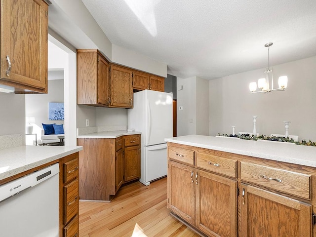 kitchen featuring white appliances, brown cabinetry, light wood-style flooring, light countertops, and pendant lighting