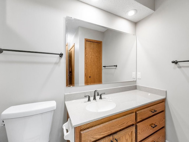 bathroom with vanity, toilet, and a textured ceiling