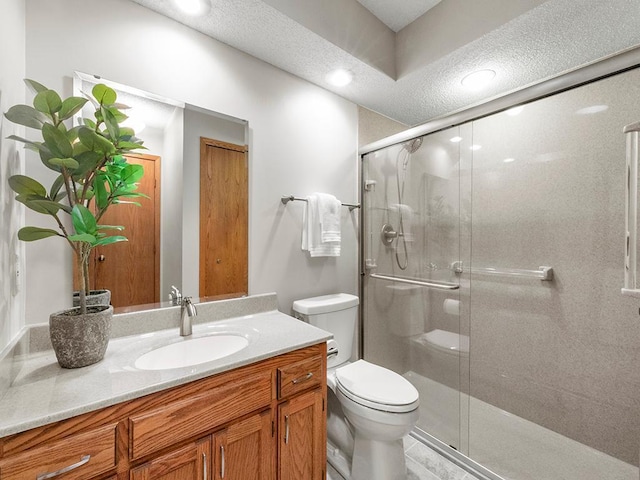 full bathroom featuring vanity, toilet, a shower stall, and a textured ceiling