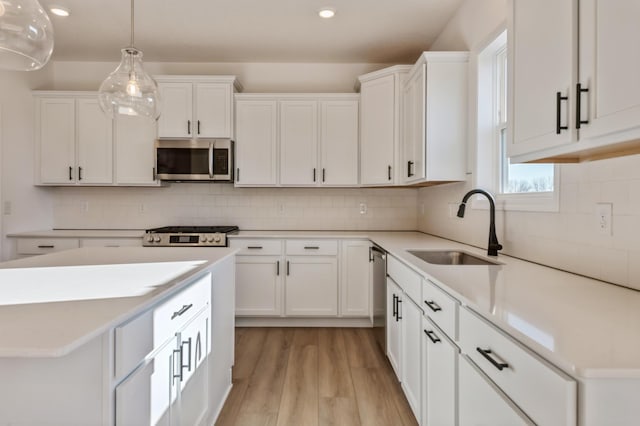 kitchen featuring white cabinetry, stainless steel appliances, sink, and pendant lighting