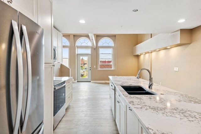 kitchen with sink, light stone counters, white cabinets, and appliances with stainless steel finishes