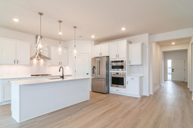 kitchen with appliances with stainless steel finishes, a kitchen island with sink, white cabinets, decorative light fixtures, and sink