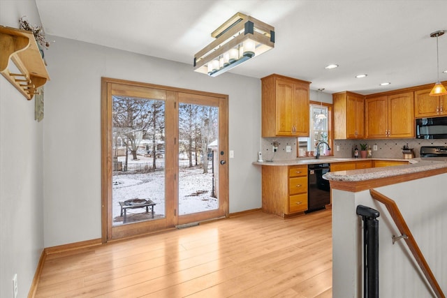 kitchen featuring sink, tasteful backsplash, decorative light fixtures, light wood-type flooring, and black appliances