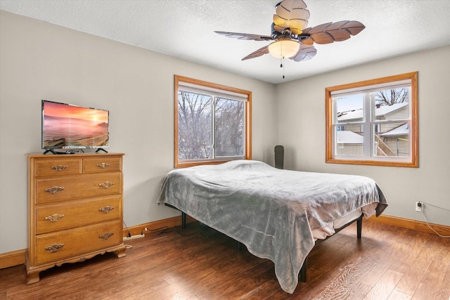 bedroom featuring ceiling fan, a textured ceiling, and dark hardwood / wood-style flooring