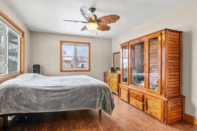 bedroom with ceiling fan, hardwood / wood-style floors, and a textured ceiling