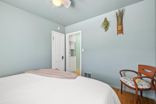 bedroom with ceiling fan, wood finished floors, visible vents, and baseboards