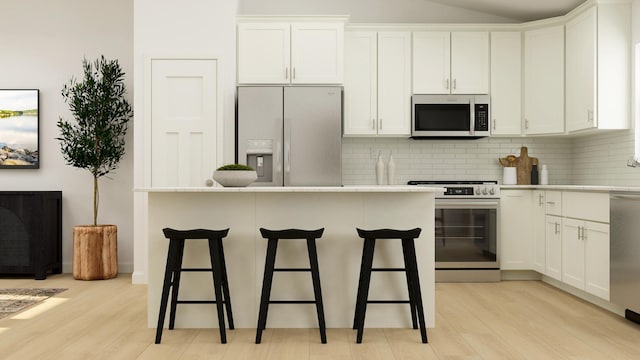 kitchen featuring a kitchen breakfast bar, white cabinets, light hardwood / wood-style floors, and appliances with stainless steel finishes