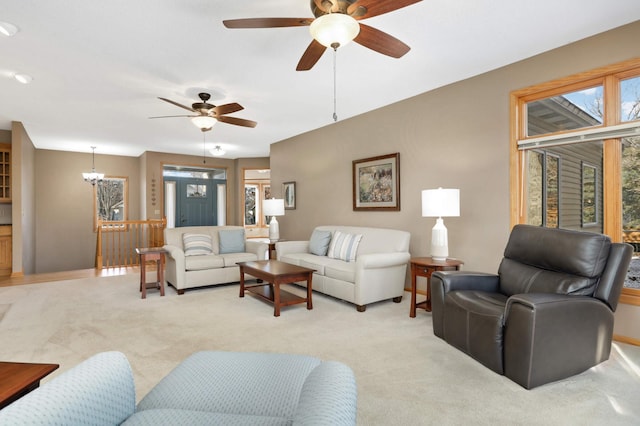 carpeted living room with ceiling fan with notable chandelier