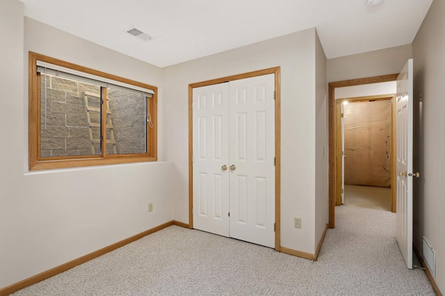 unfurnished bedroom with light colored carpet and a closet