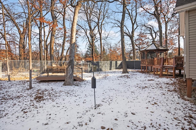 yard layered in snow with a wooden deck and a gazebo