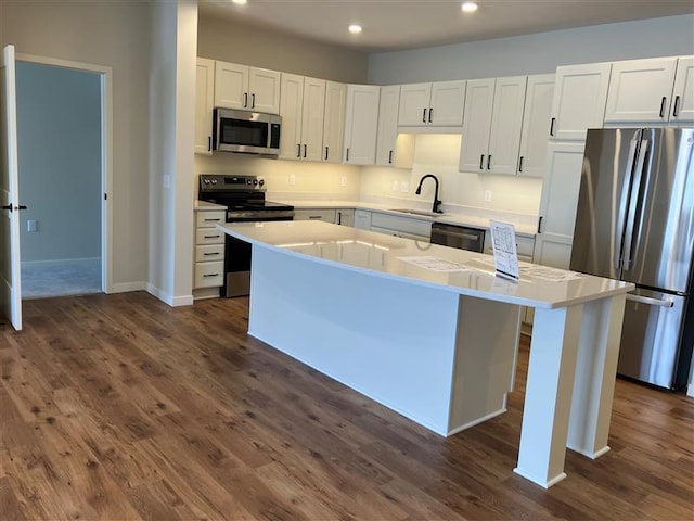 kitchen featuring white cabinetry, sink, dark hardwood / wood-style flooring, a center island, and stainless steel appliances