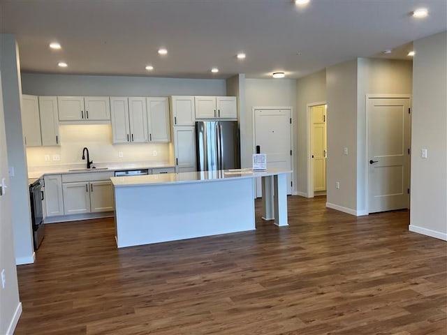 kitchen featuring sink, dark wood-type flooring, appliances with stainless steel finishes, white cabinetry, and a kitchen island