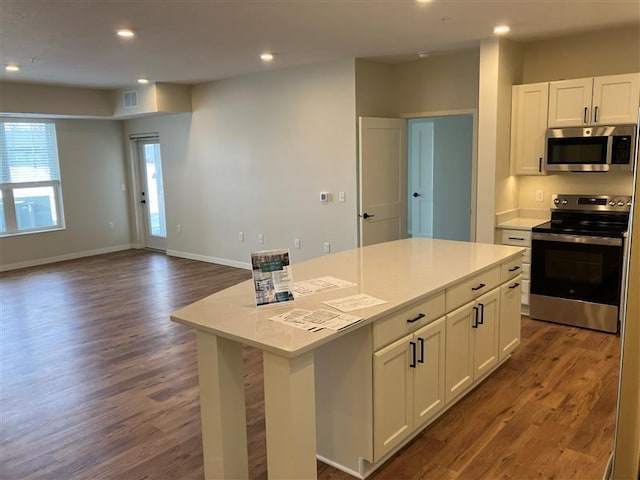 kitchen featuring appliances with stainless steel finishes, dark hardwood / wood-style flooring, a center island, and white cabinets