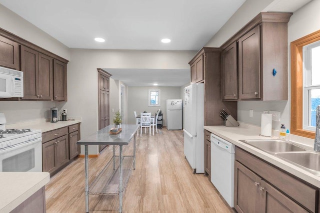 kitchen with light wood-type flooring, white appliances, and light countertops