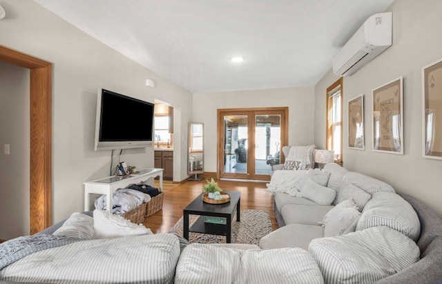 living room featuring french doors, light wood-type flooring, and a wall unit AC