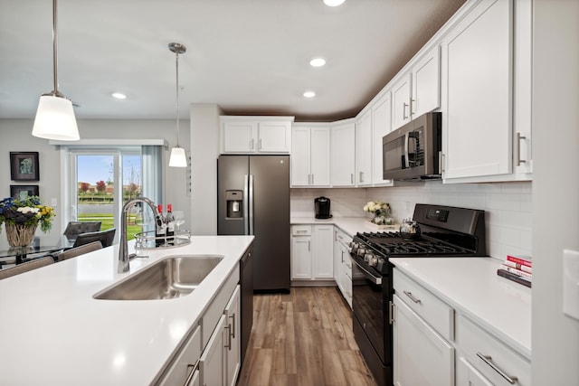 kitchen with white cabinets, black appliances, decorative light fixtures, tasteful backsplash, and sink