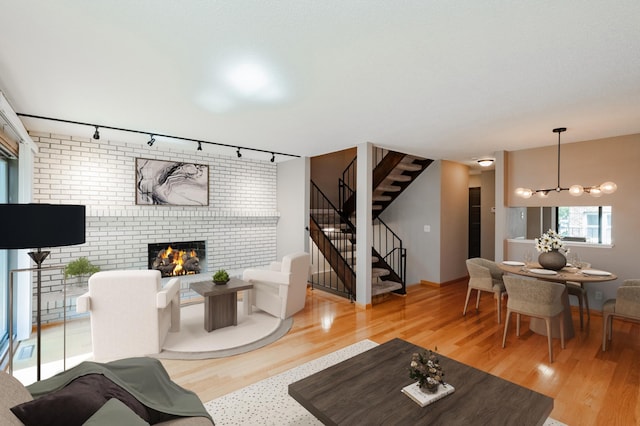 living room with hardwood / wood-style flooring, rail lighting, a notable chandelier, and a fireplace