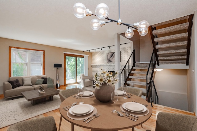 dining area with a textured ceiling, a brick fireplace, a chandelier, and rail lighting