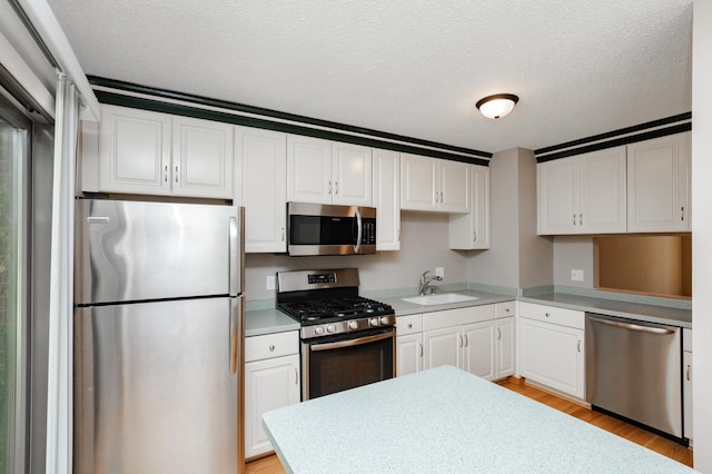 kitchen with sink, white cabinetry, appliances with stainless steel finishes, and a textured ceiling