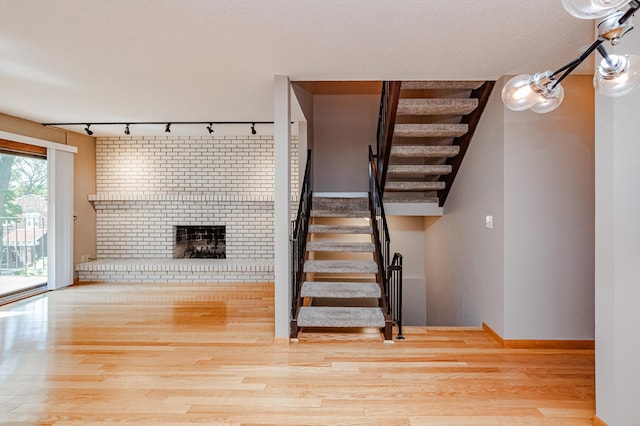 stairway with track lighting, a fireplace, and hardwood / wood-style flooring