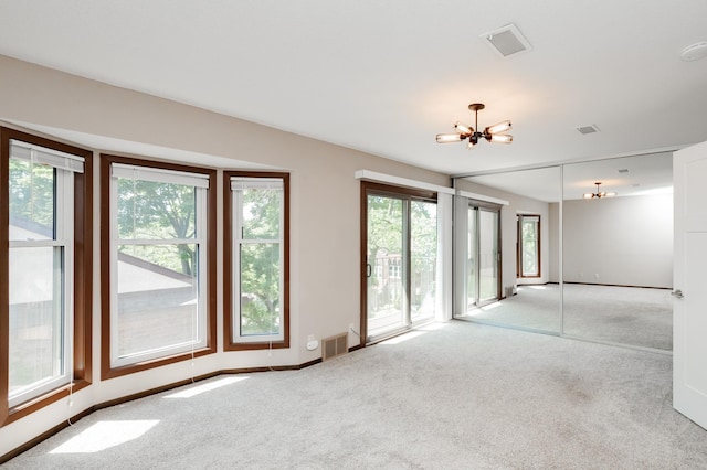 unfurnished room featuring an inviting chandelier and light colored carpet